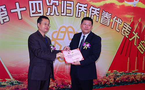 省僑聯(lián)領(lǐng)導(dǎo)楊春華（左）向新會(huì)區(qū)委副書記增雄偉（右）頒發(fā)名譽(yù)主席聘書