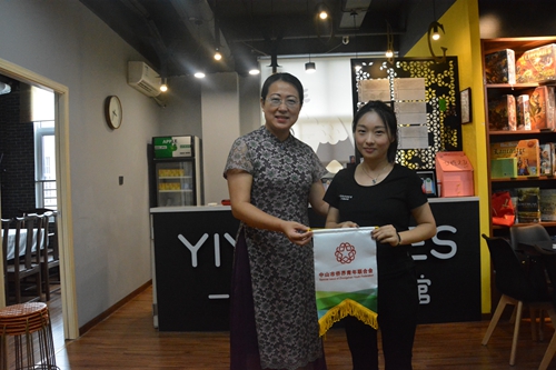市僑青聯(lián)副會長凱莉（左一）向李穎婷（右一）贈送會旗。